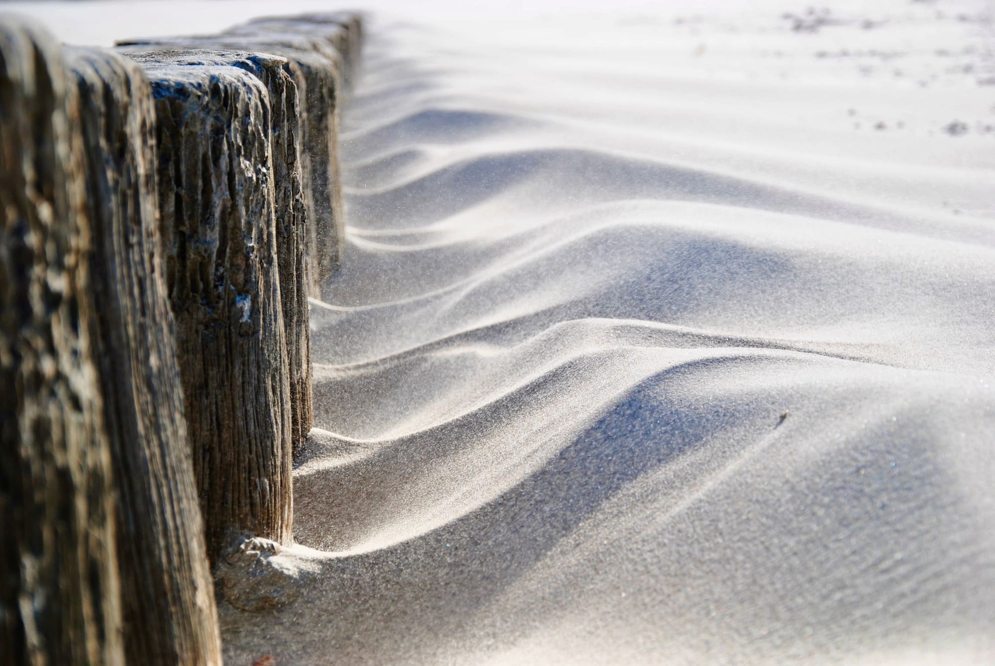 Weathered timber posts and wind-blown sand